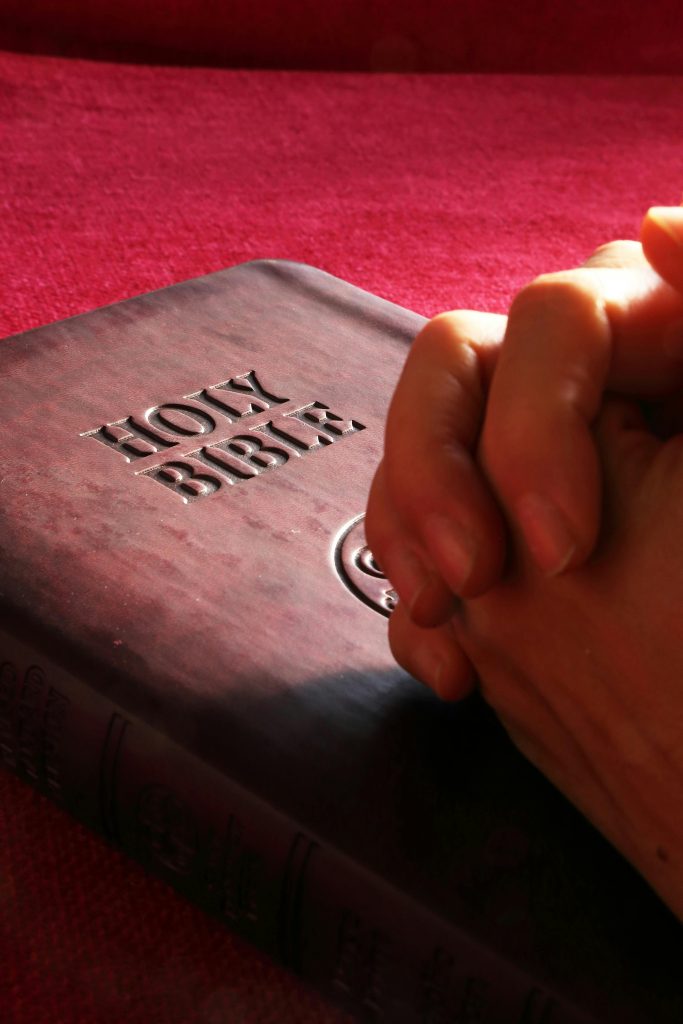pexels-photo-267559-267559 Close-up of hands praying on a Holy Bible, symbolizing faith and spirituality.